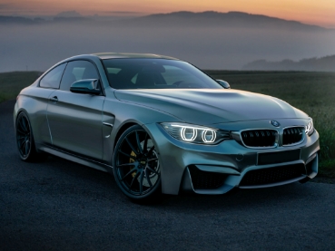 夕日が沈みかける背景とBMW製のシルバーの車